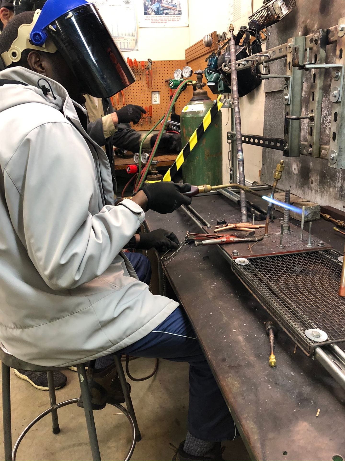 Hands-on brazing practice with torch and PPE at the HVAC School training bench