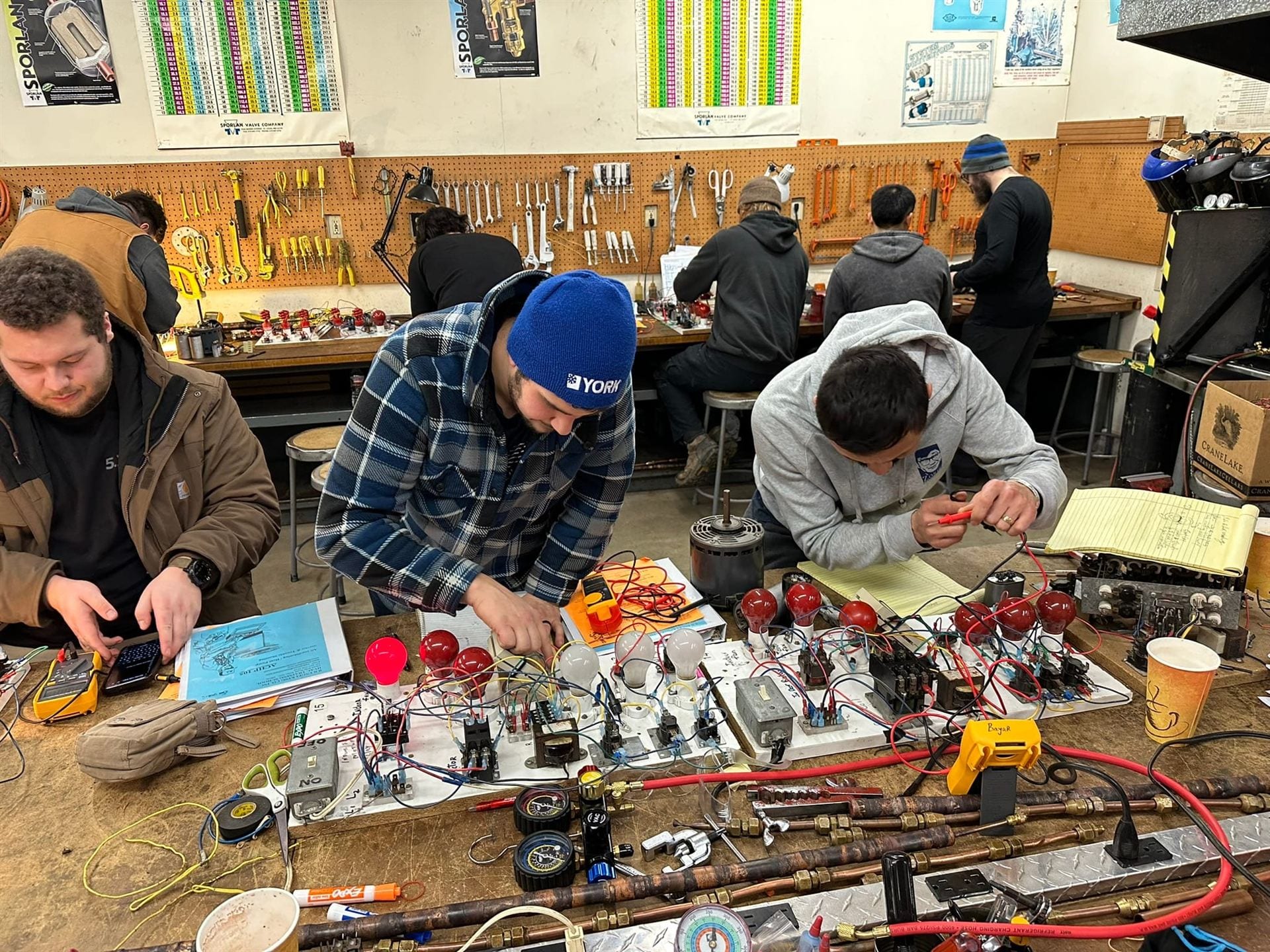 Students working on refrigeration controls and wiring boards at the bench