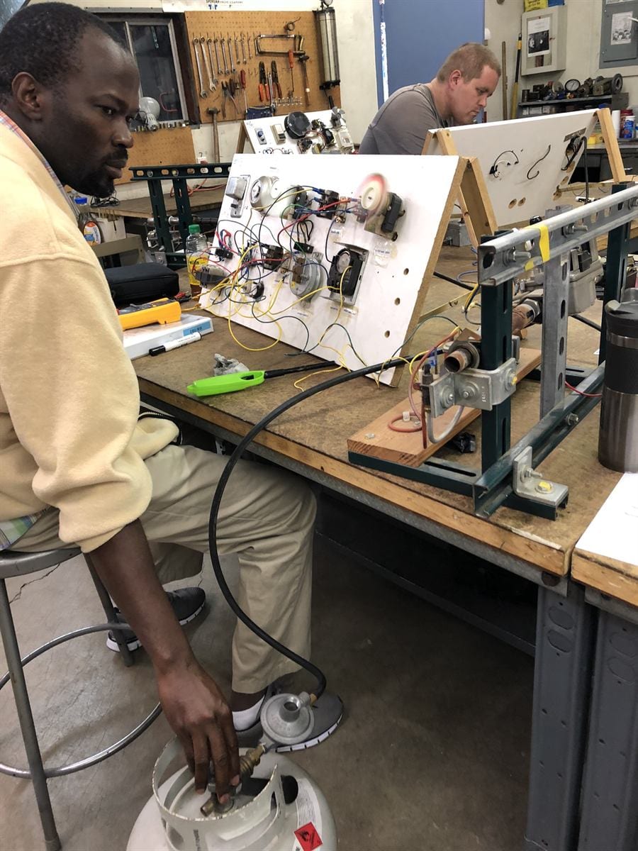 GS 102 student tracing electrical signal paths on a furnace control board